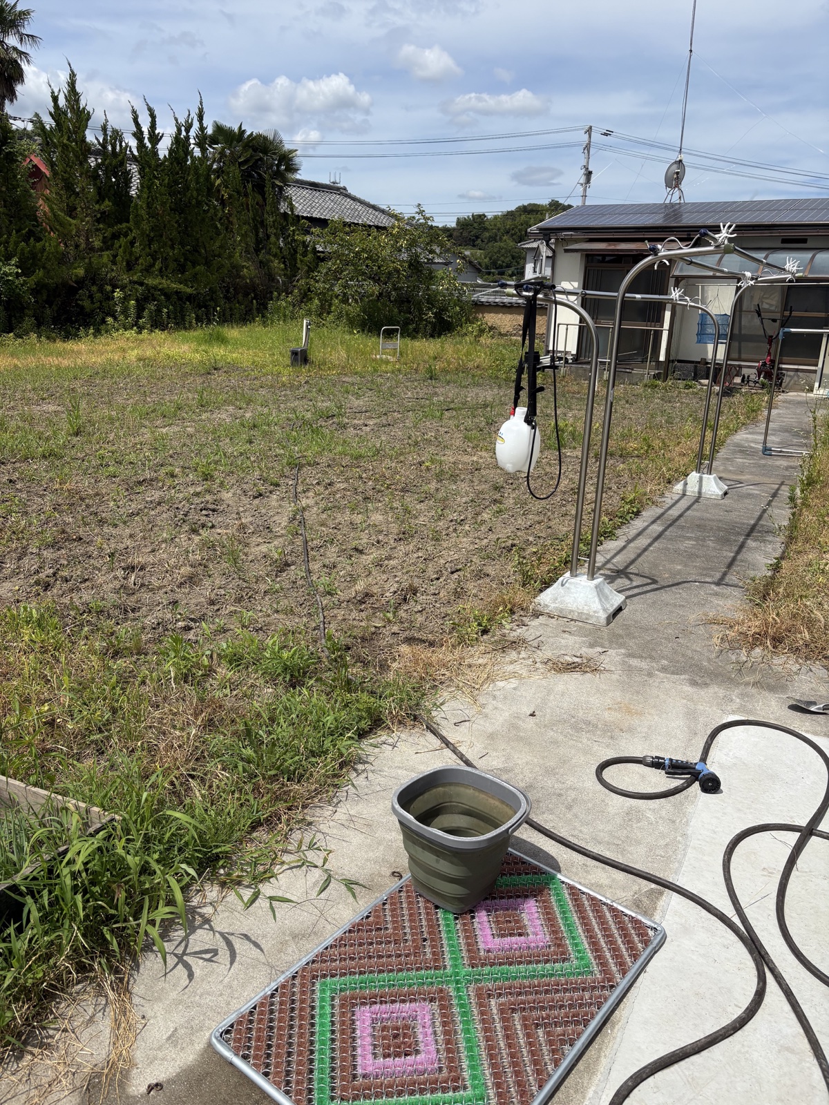 家側から見た耕うん済みの庭と散布道具